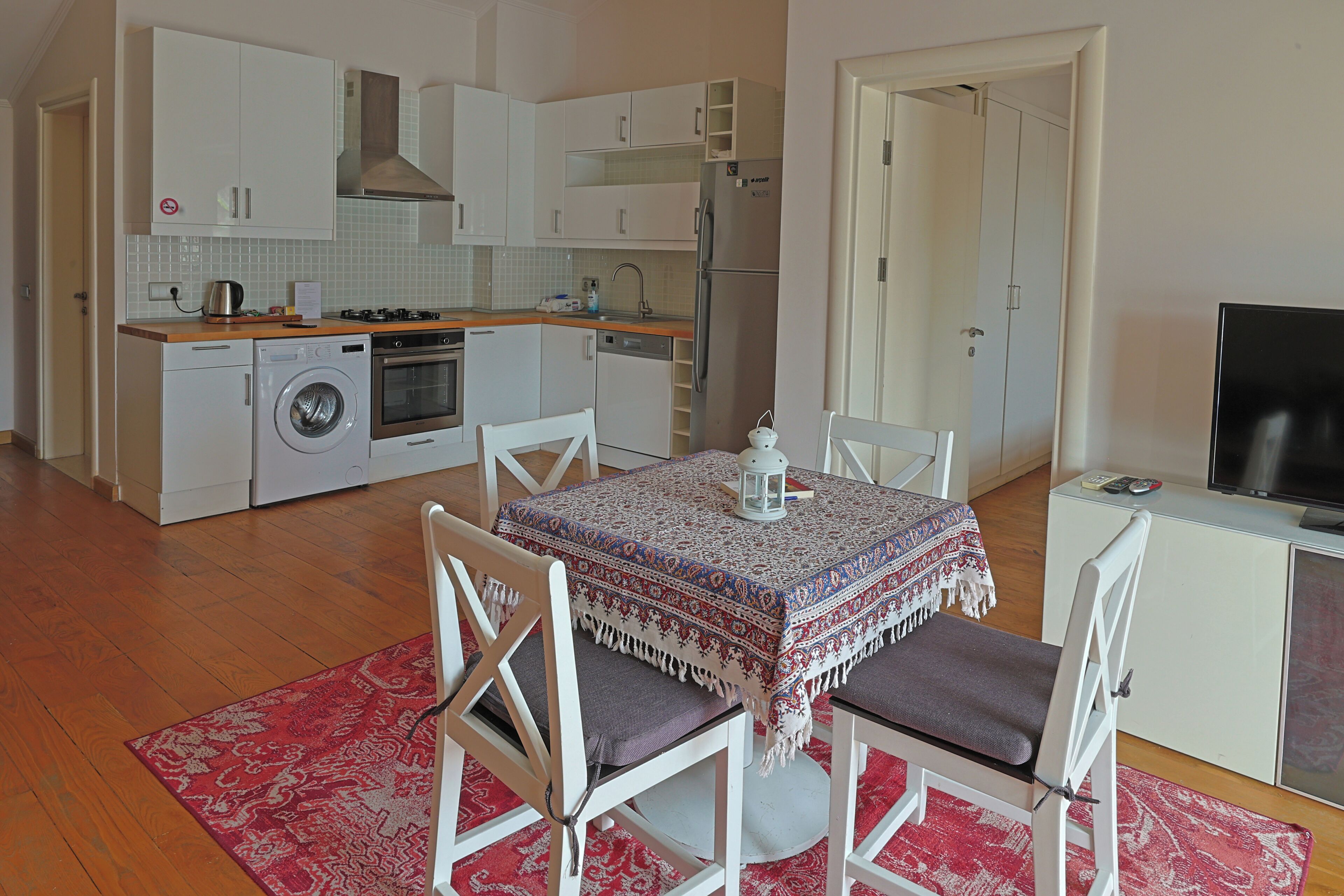 A compact kitchen with a washing machine, oven, and refrigerator.