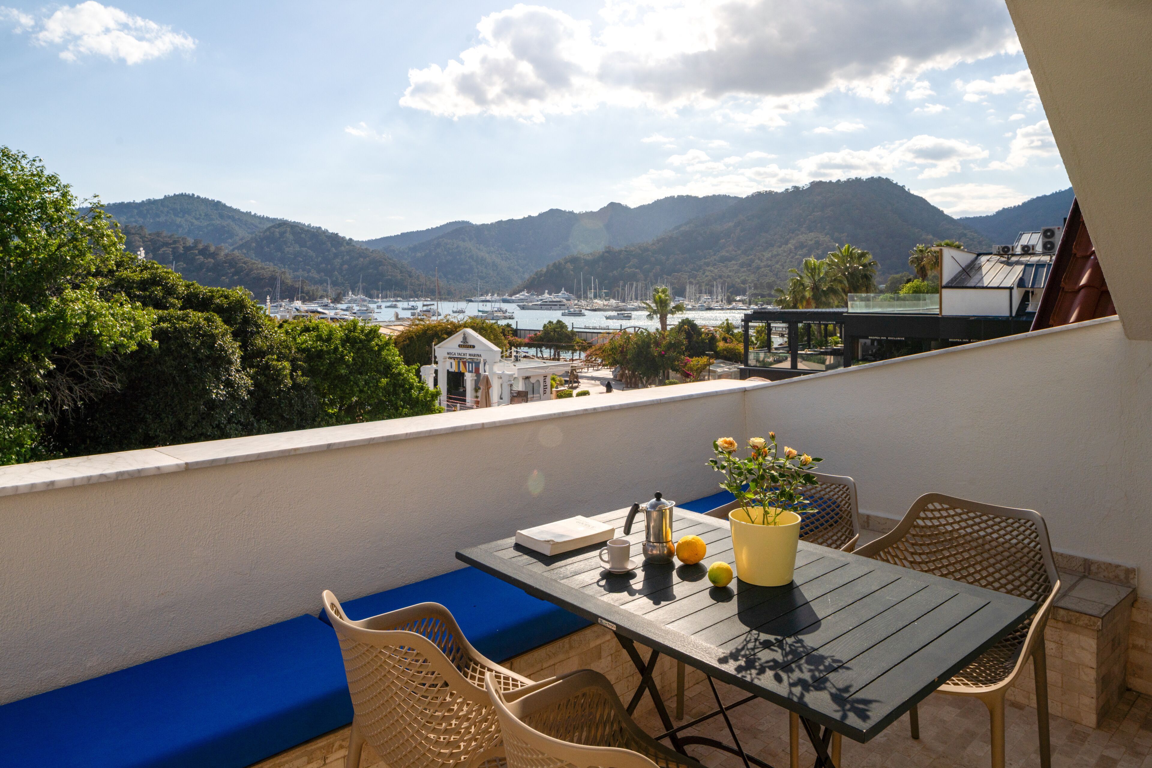 Un balcon avec une table, des chaises et une vue sur la mer et les montagnes.