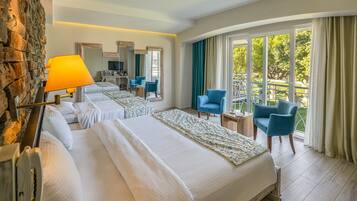 A hotel room with two beds, a sitting area with chairs, a TV, and a balcony with curtains.