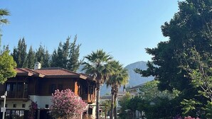Un canal con una casa de madera a la izquierda, rodeado de follaje y flores.