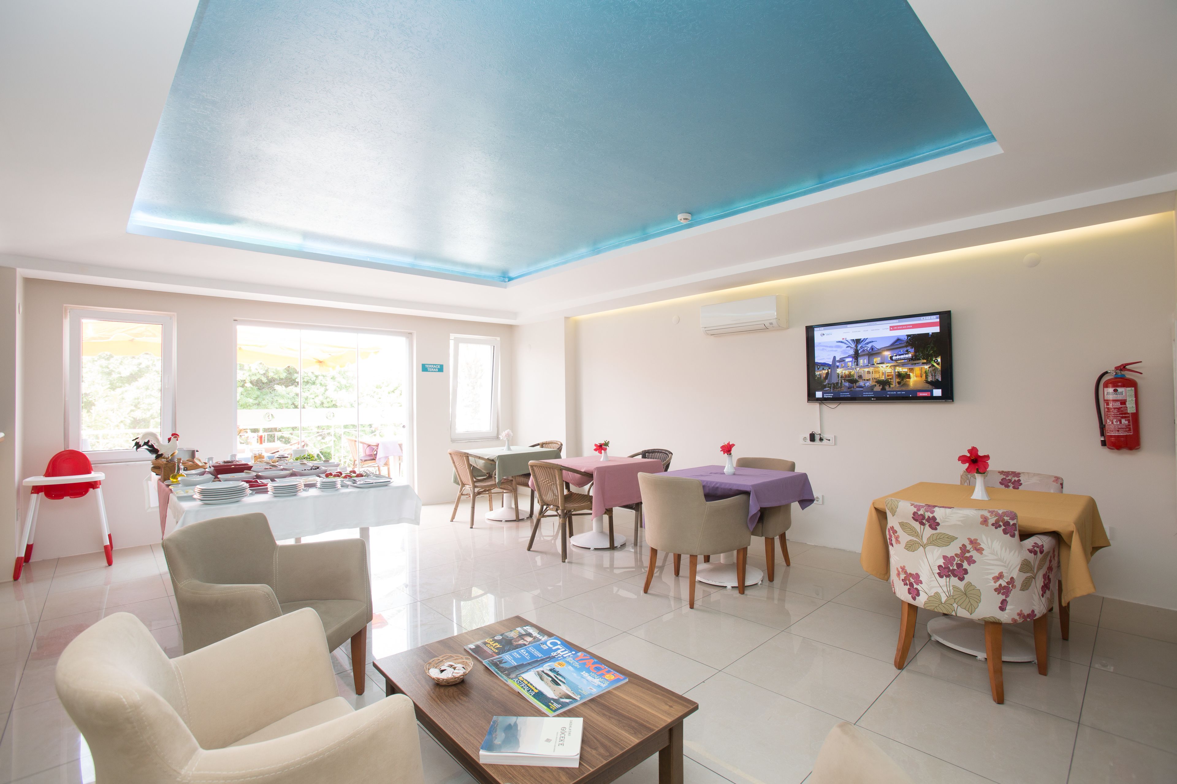 A spacious dining area with a high ceiling and a television mounted on the wall.