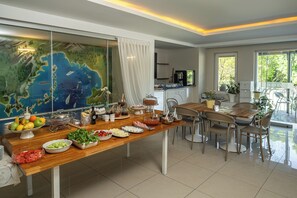 A dining area with a long wooden table, various food items, and a large map on the wall. - Dedeminn Marina Hotel (Fethiye)
