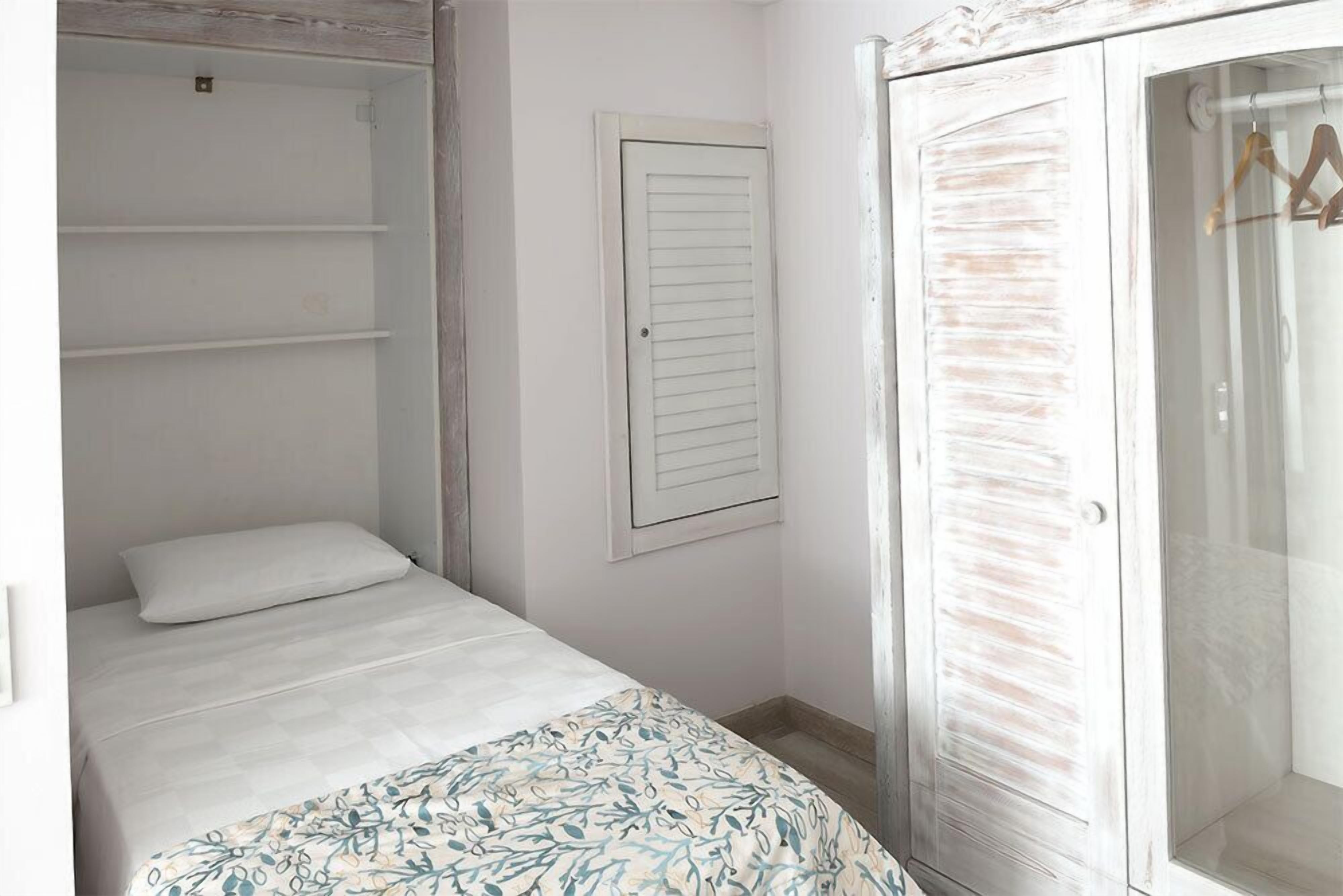 A bedroom with a bed, a wardrobe, and a door.