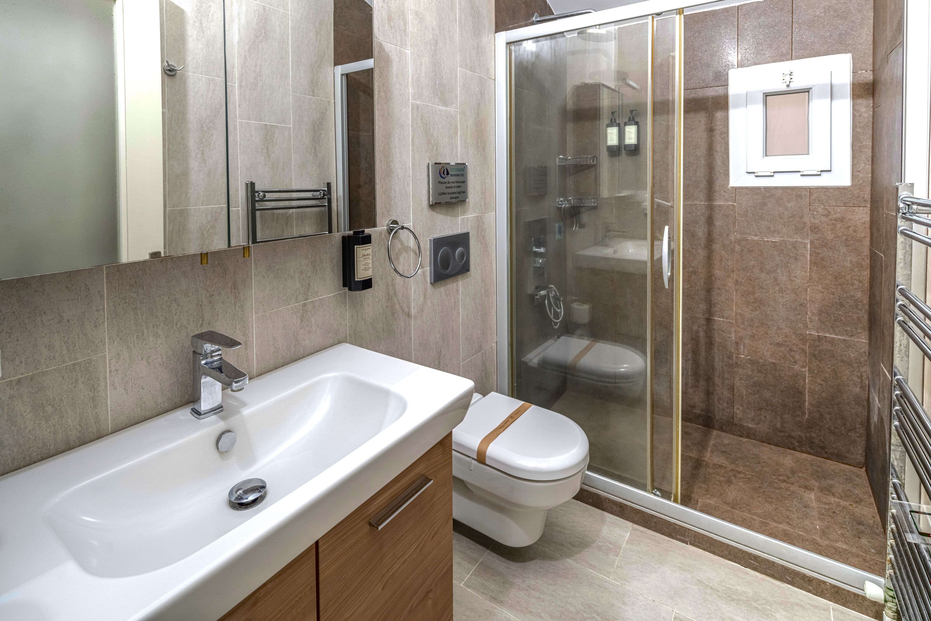 A modern bathroom with a white sink, a glass shower enclosure, and a toilet.