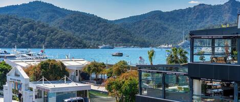 A marina with boats, a restaurant, and a coffee shop with a view of the water and mountains.