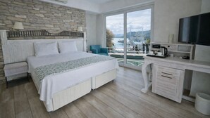 Un dormitorio con cama, escritorio, televisor y vista al puerto.