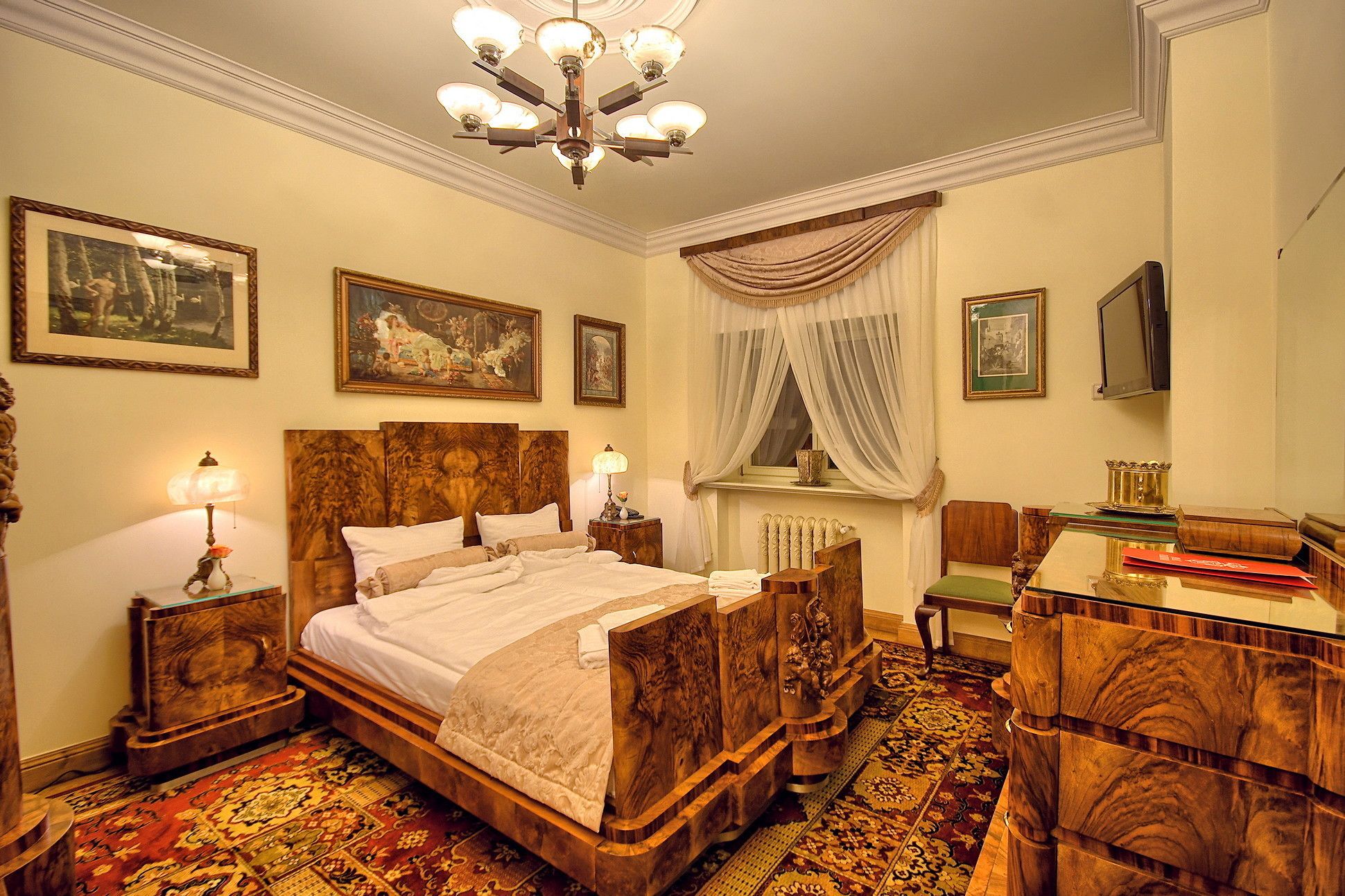A traditional bedroom with a four-poster bed, a chandelier, and a large mirror.