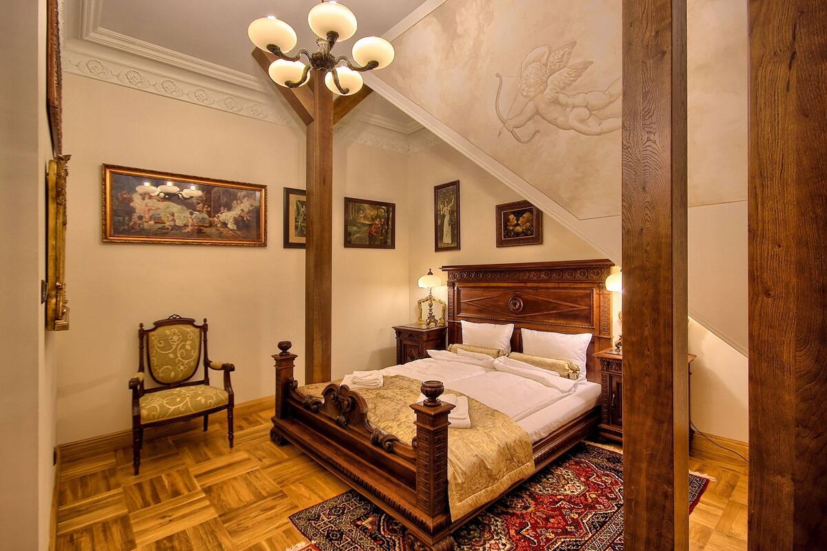 Um quarto tradicional com uma cama de dossel, um candelabro e um grande mural no teto.