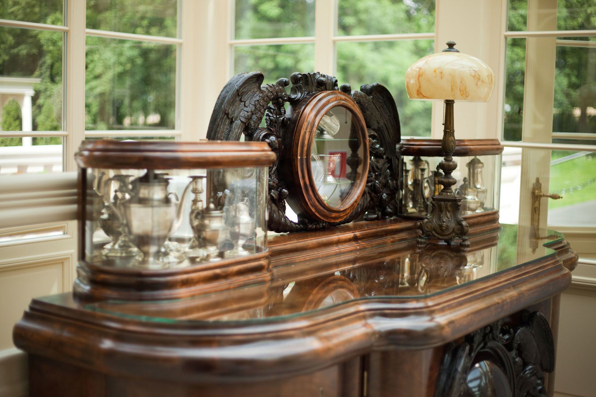A wooden table with a mirror, a lamp, and glass objects.