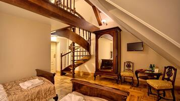 Un dormitorio con una escalera de madera, una cama con edredón floral, una silla y una mesita con botellas.