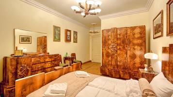 Habitación de hotel con una cama grande, muebles de madera, un candelabro y cuadros enmarcados en las paredes.