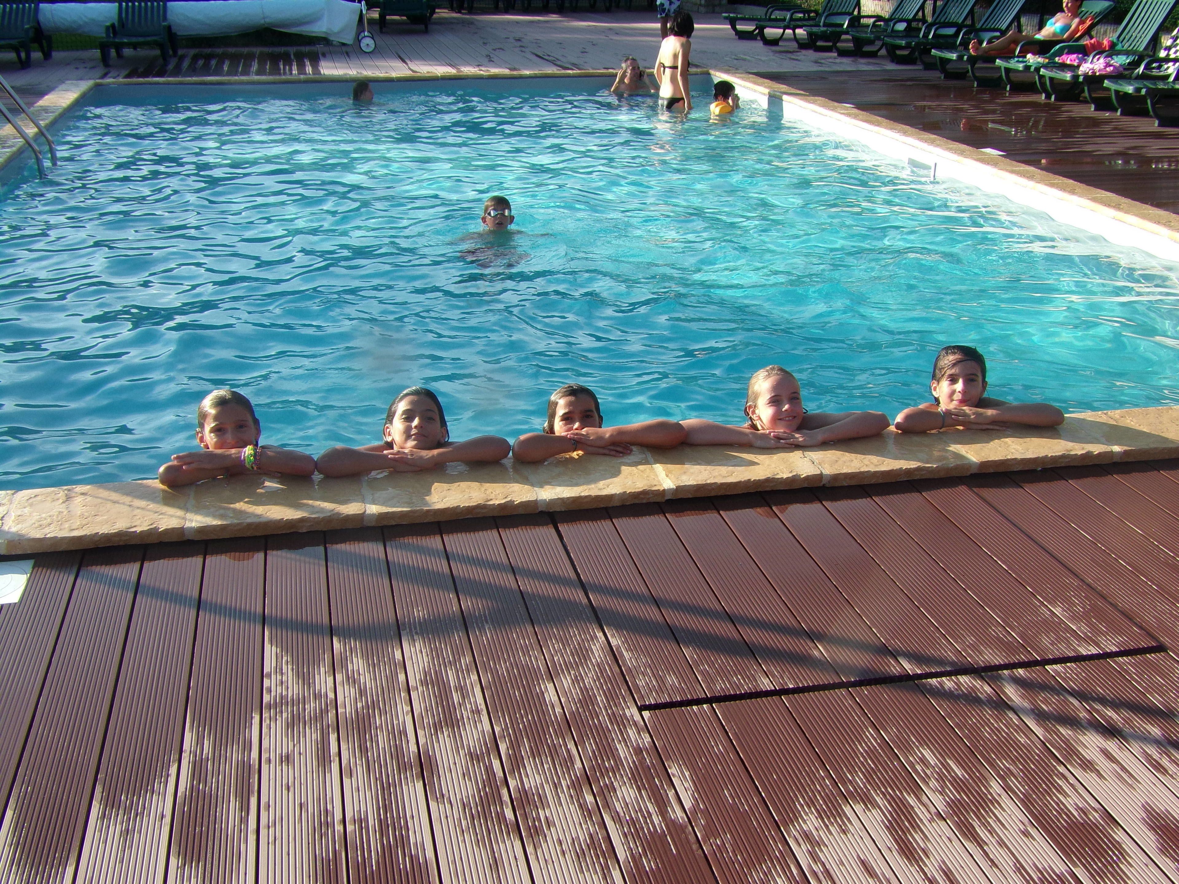 A swimming pool with a wooden deck and lounge chairs.