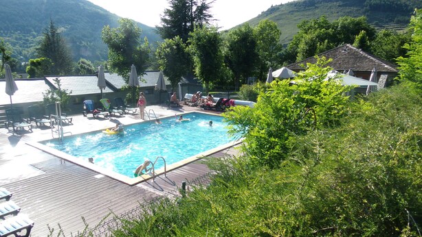 A swimming pool surrounded by greenery, with a view of hills in the background. - Domaine Aigoual Cévennes (Meyrueis)