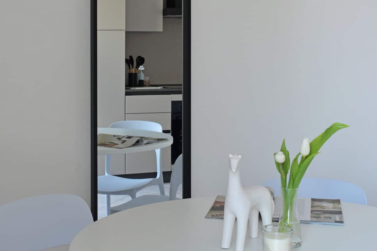 Ein runder, weißer Tisch mit einer Vase voller weißer Blumen und einer Giraffe aus Porzellan.