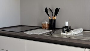 Un plan de travail de cuisine avec une planche à découper noire, une planche à découper en marbre blanc, un bocal de pâtes, une bouteille de FSK et un torchon.
