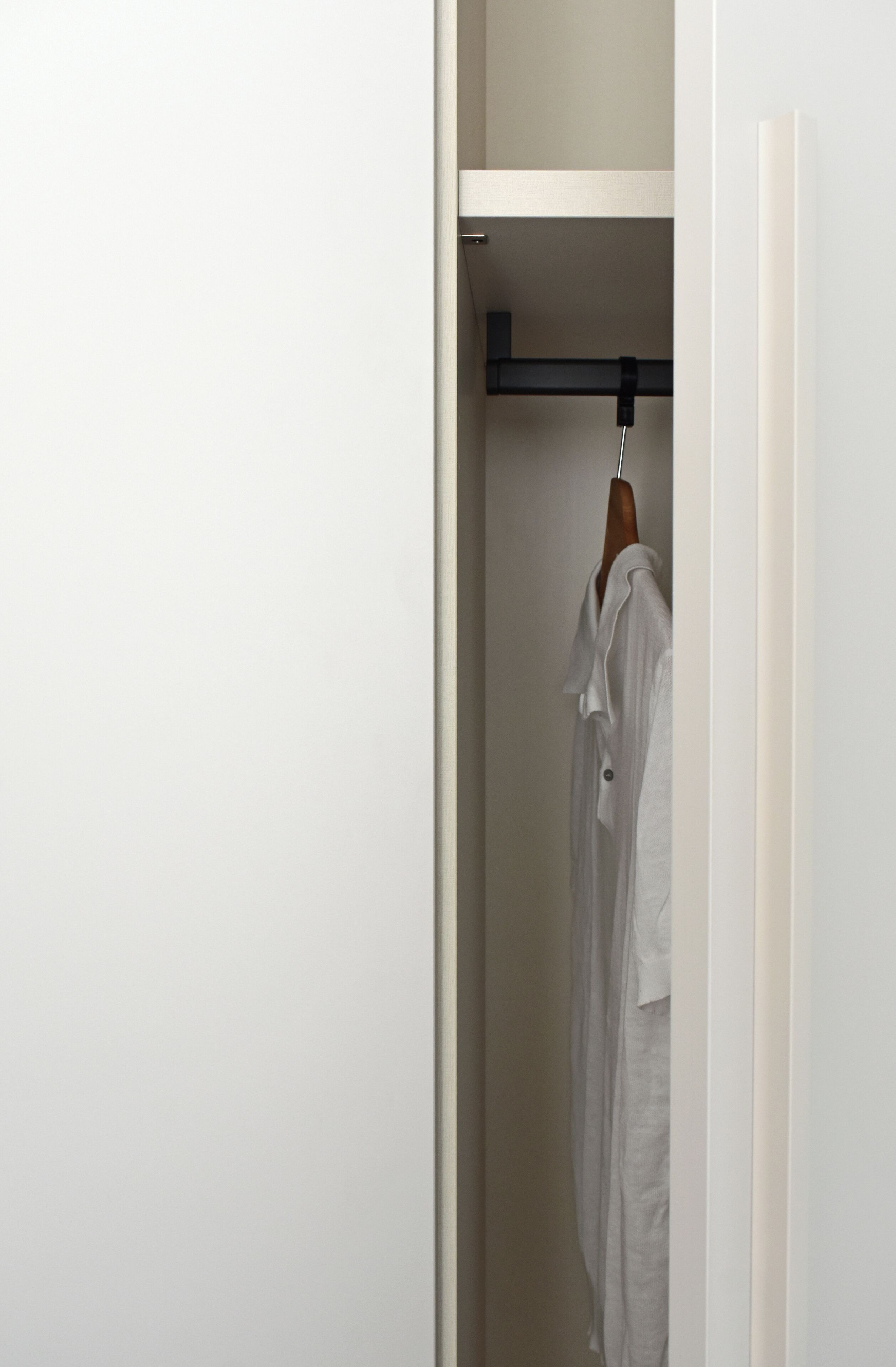 A white closet with a wooden hanger rod.