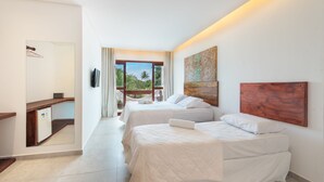 A hotel room with two beds, a wooden headboard, a large window with a view of palm trees, and a small desk with a mirror. - Pousada Quatro Estações (Ipojuca)