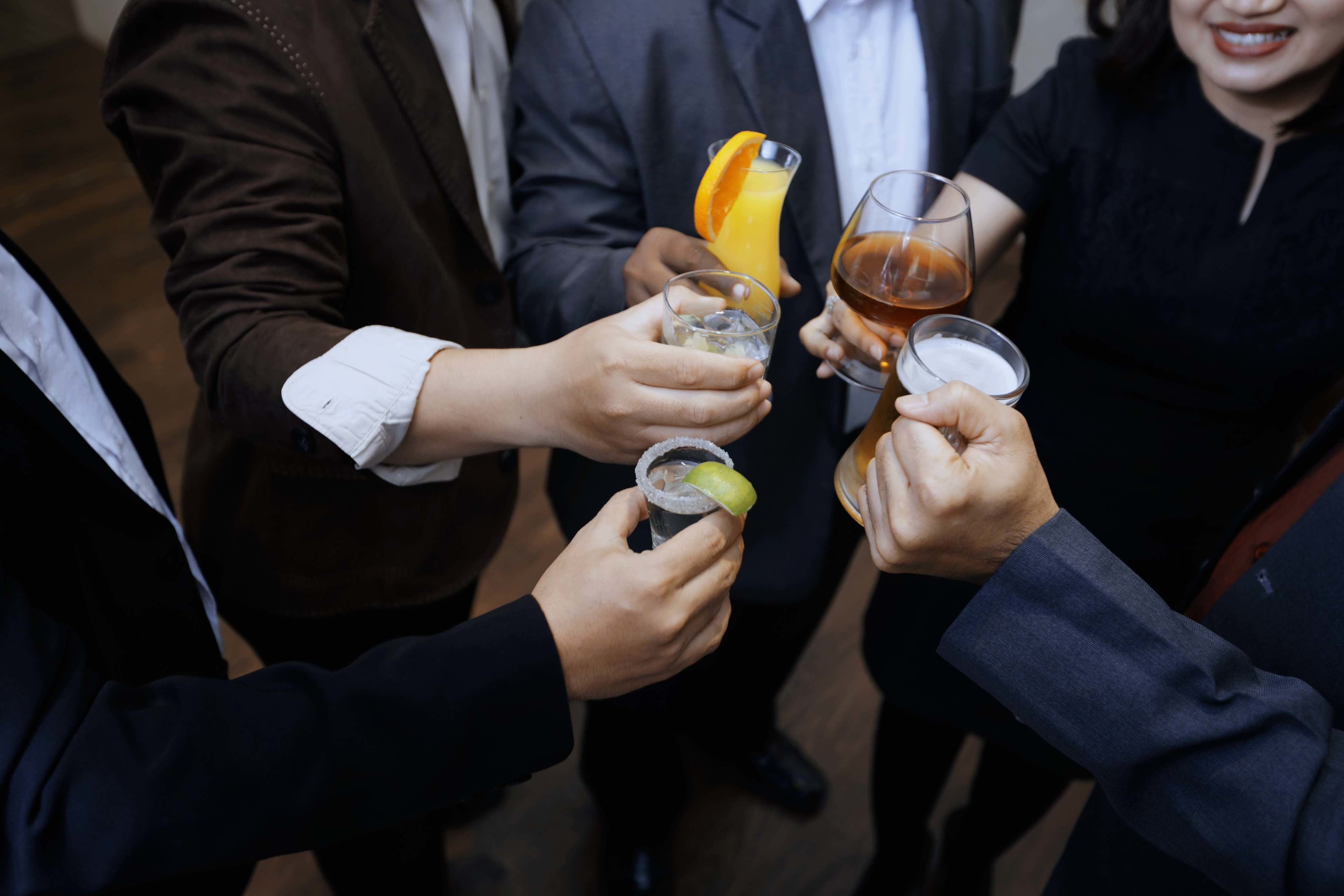 A group of people toasting with drinks, including a glass with a lime wedge.