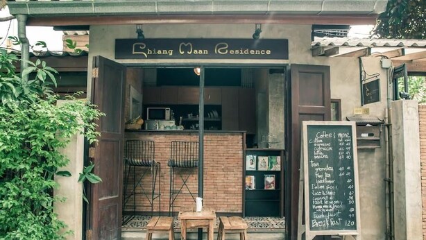 Uma charmosa cafeteria chamada "Chiang Wan Residence", com decoração rústica, menu em lousa e uma pequena área de estar ao ar livre.
