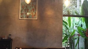 Uma sala de estar acolhedora com uma mesa de centro de madeira, um sofá com almofadas e uma obra de arte emoldurada na parede.