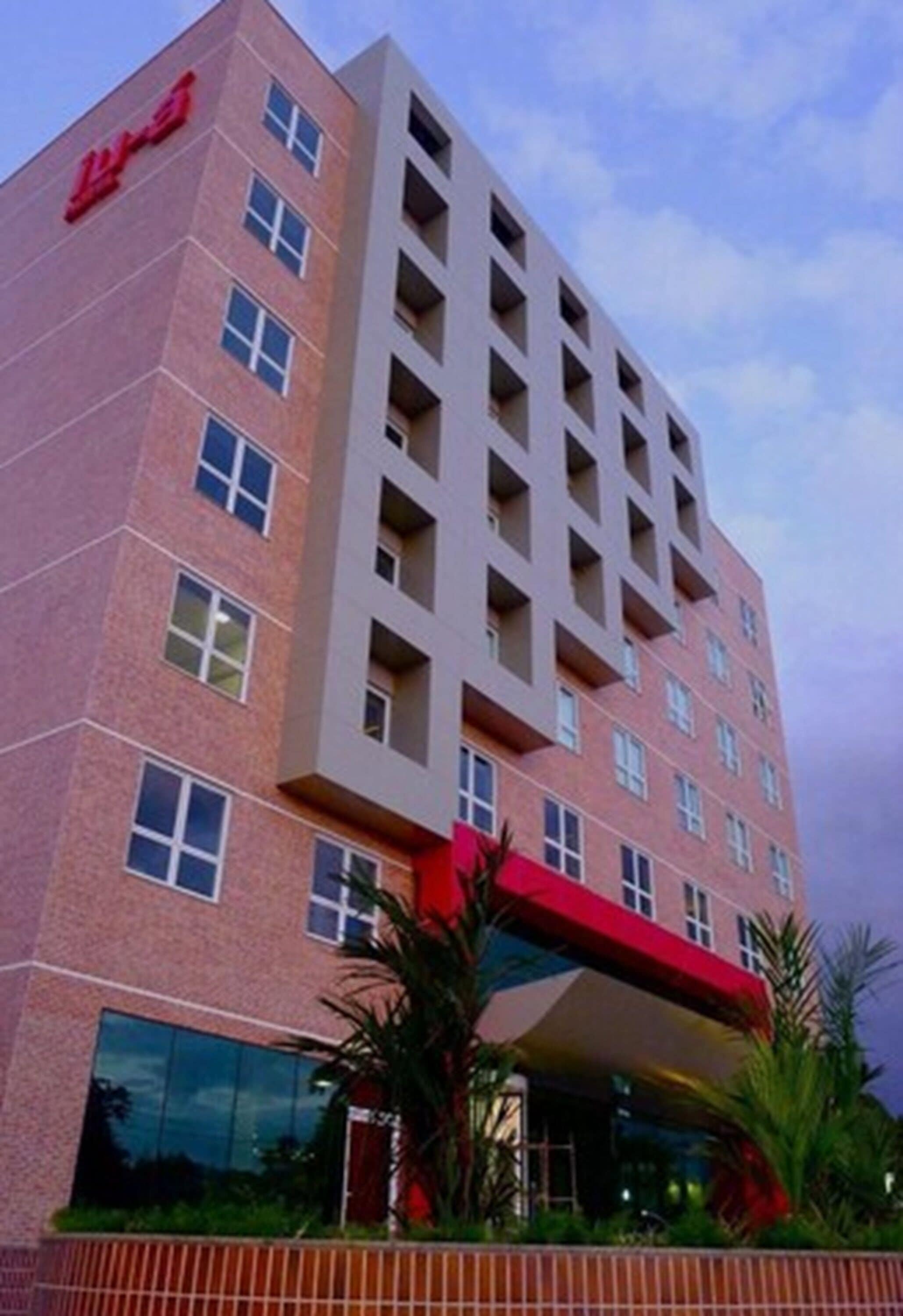 Un hotel de varios pisos con un letrero rojo llamativo a la izquierda.