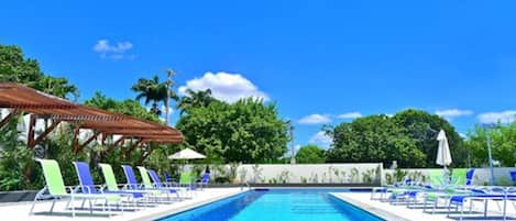 Una piscina al aire libre, sillones reclinables de piscina