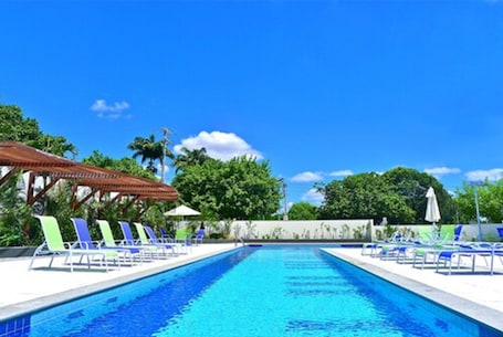 Una piscina al aire libre, sillones reclinables de piscina