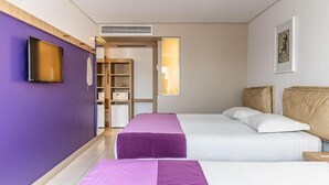 Une chambre d’hôtel avec deux lits, une télévision, une armoire et une salle de bain visible à travers une porte ouverte.