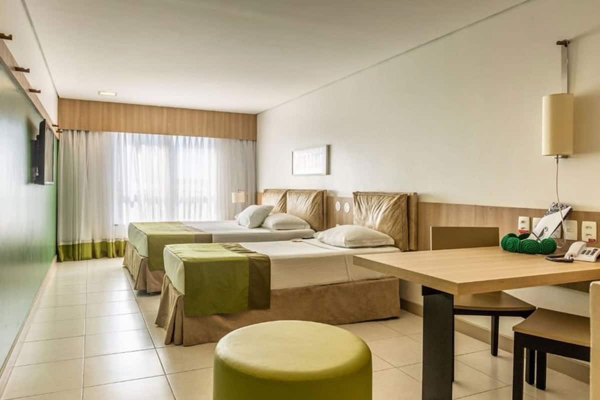 Una habitación de hotel con una cama, dos mesitas de noche, un escritorio y una silla.