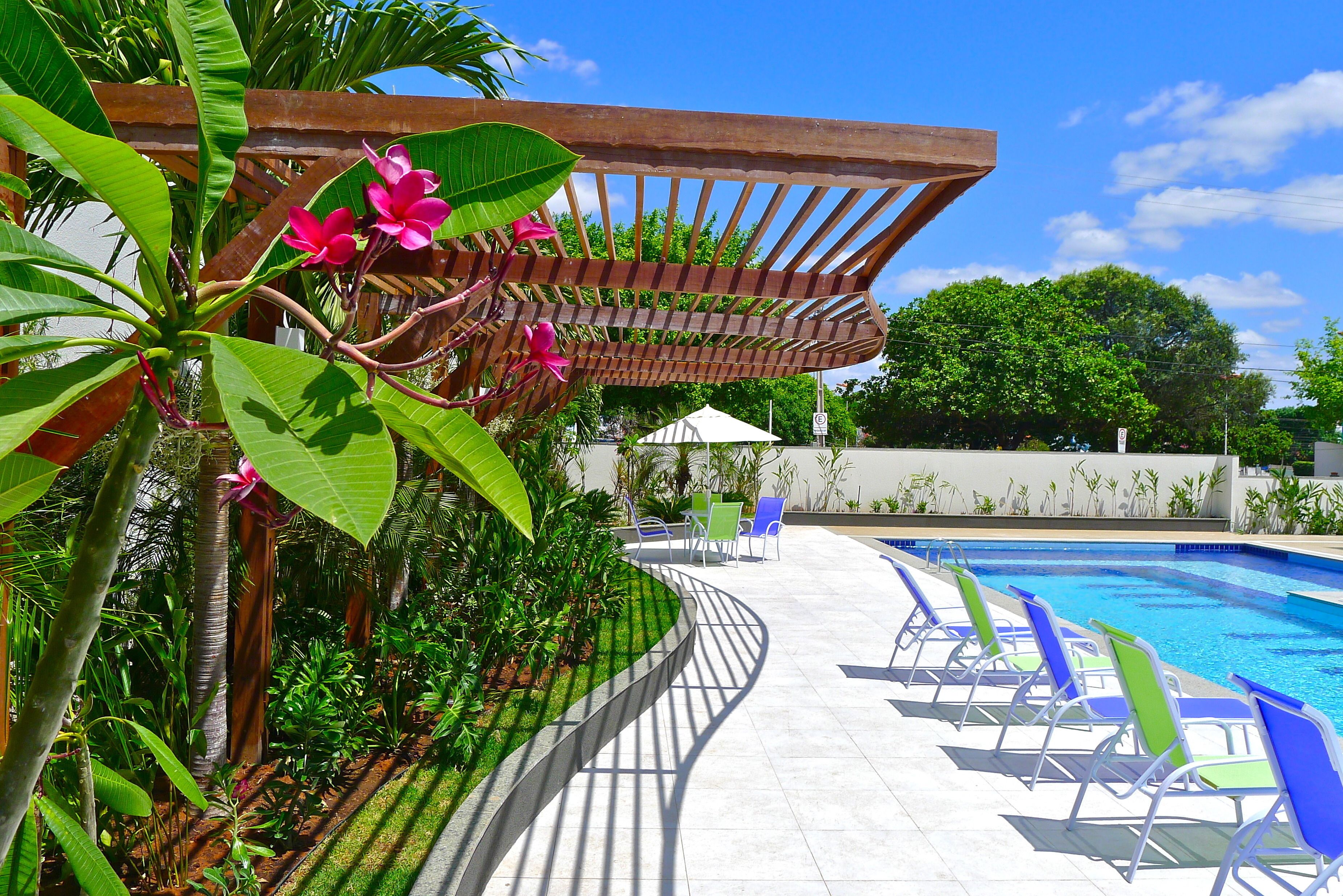 Zona de piscina amb gandules, una pérgola i vegetació exuberant.