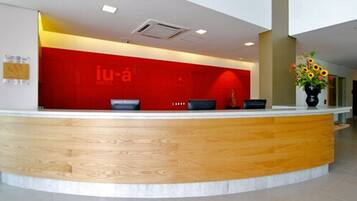 A hotel reception desk with a red wall and a wooden counter.