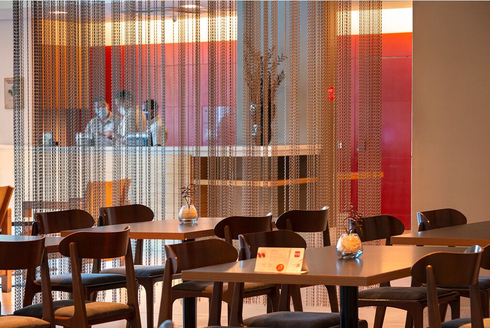 Ein Restaurant mit Tischen und Stühlen, einer Wand mit vertikalen Verzierungen und einer sichtbaren Speisekarte auf einem Tisch.