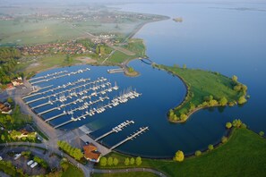 An aerial view of a marina with multiple docks and boats, surrounded by green fields and a small town in the background. - Résidence Marina Holyder (Giffaumont-Champaubert)
