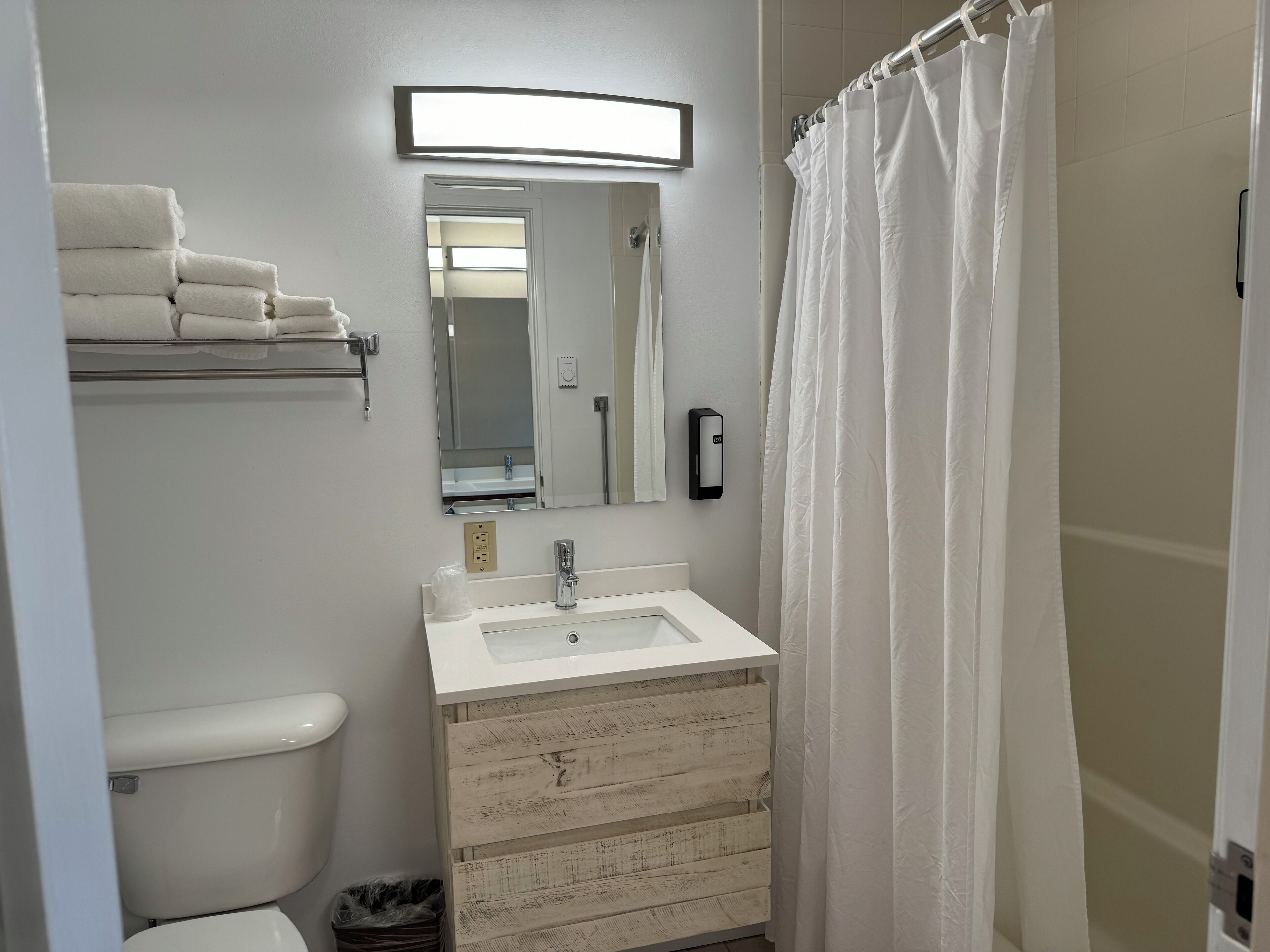 A bathroom with a toilet, sink, mirror, towel rack, and shower curtain.