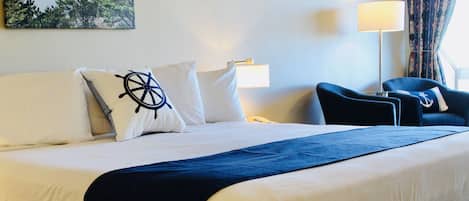 Habitación de hotel con cama, una silla, una lámpara y un cuadro en la pared.