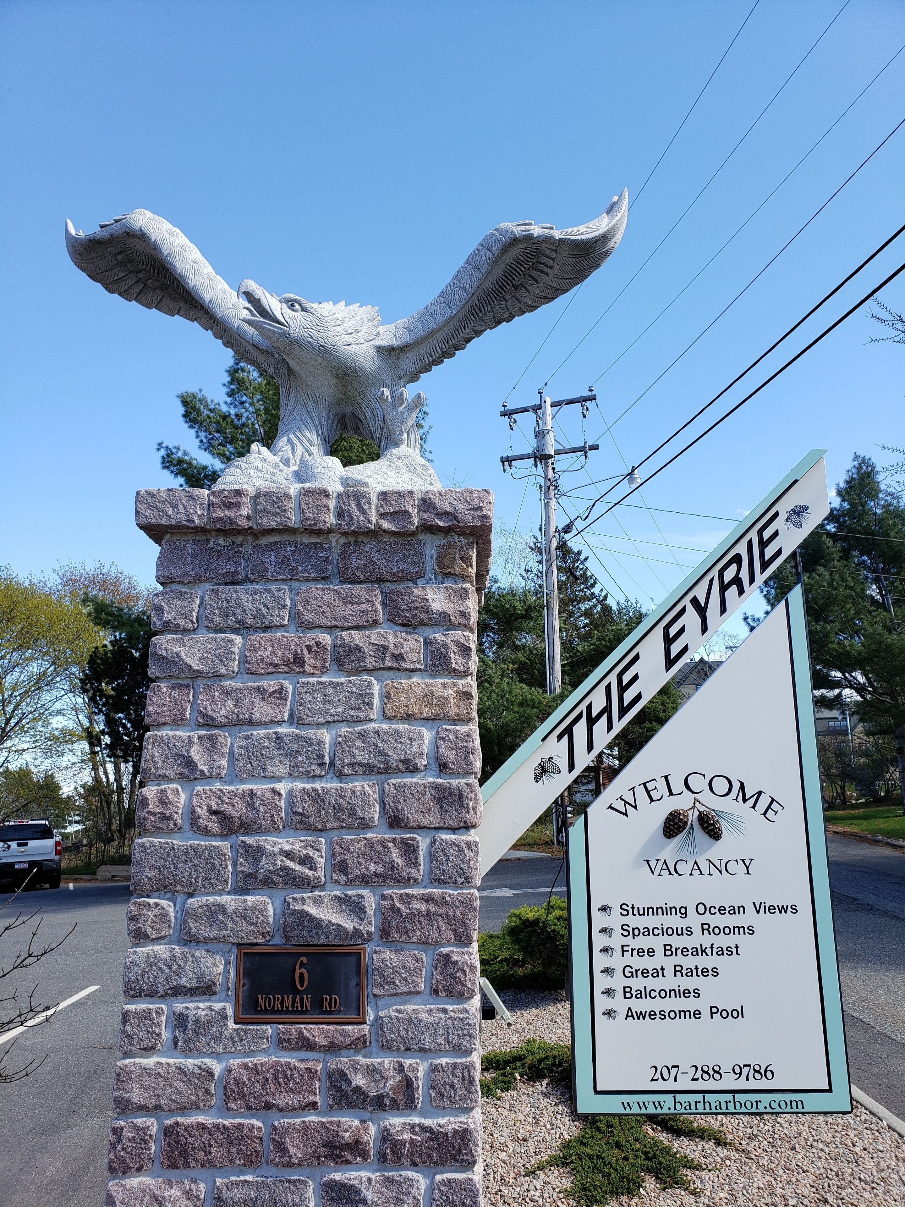 A welcome sign for The Eyrie, highlighting features like stunning ocean views, spacious rooms, free breakfast, great rates, balconies, and an awesome pool.