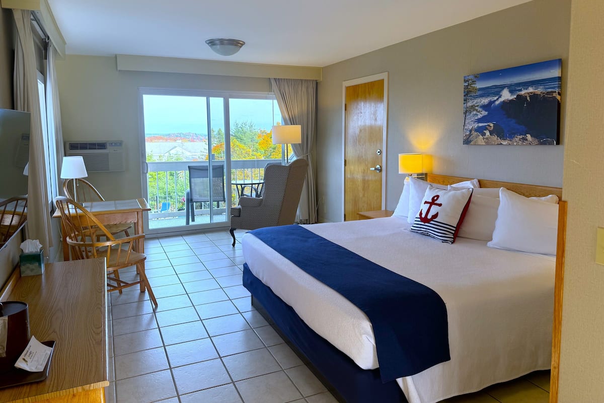 Quarto de hotel com cama, escrivaninha, cadeira, mesa e varanda com vista.