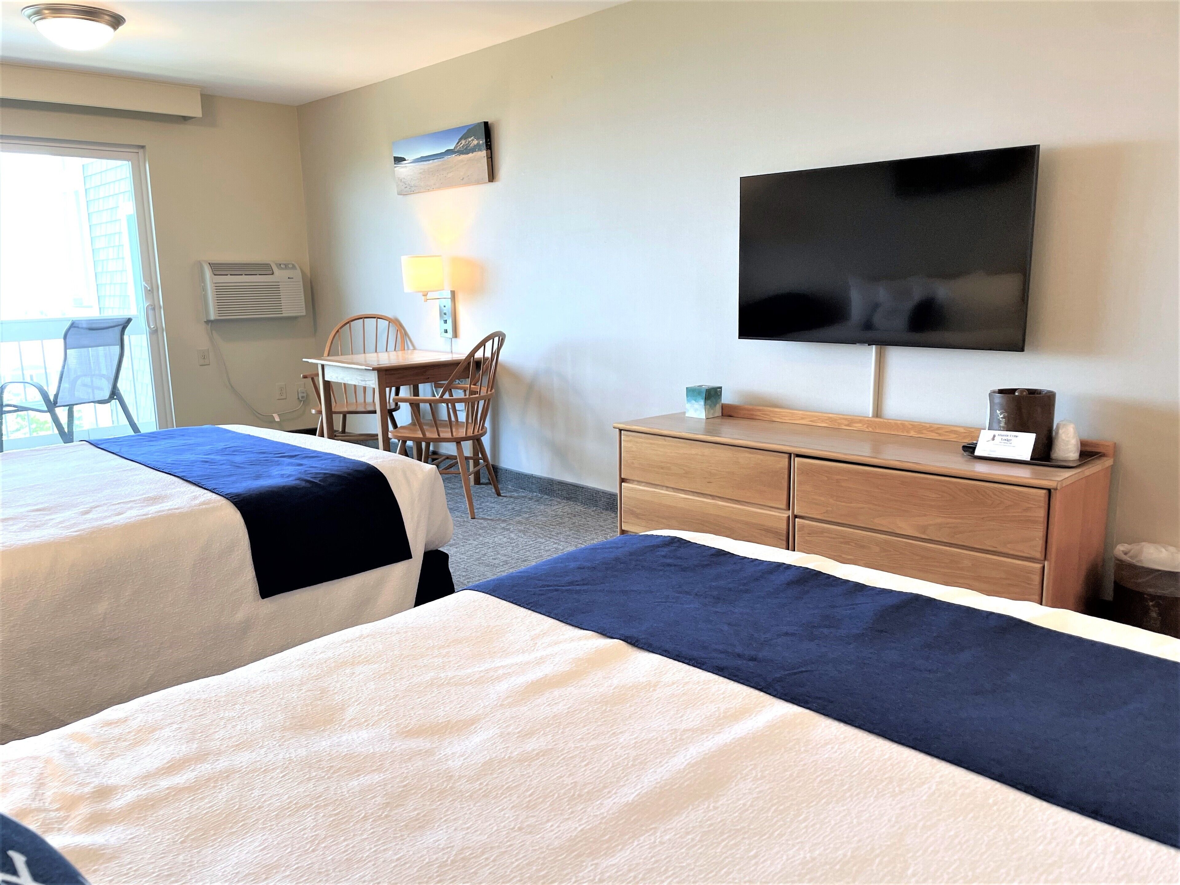 Hotellihuone, jossa on kaksi sänkyä, työpöytä tuoleineen, televisio ja lipasto.