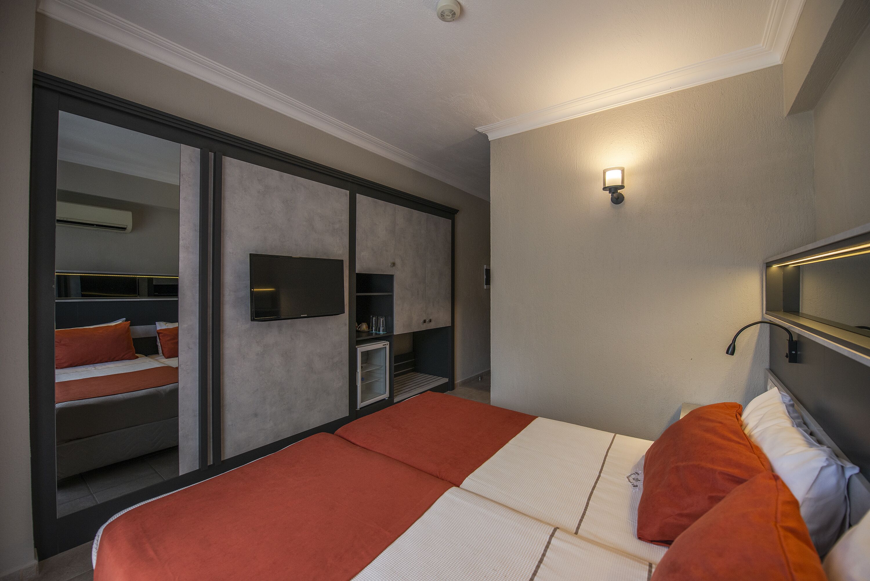 Una camera d'albergo moderna con un letto grande, un armadio, una TV e una piccola zona salotto.