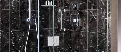 A modern shower with a glass enclosure, a handheld showerhead, and a wall-mounted control panel.