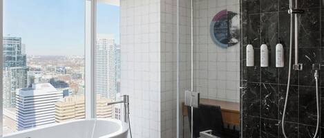 Une salle de bain moderne avec une baignoire, une douche et une vue sur la ville.