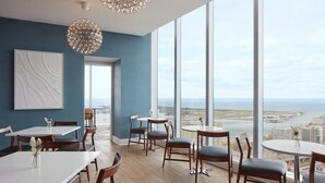 Un comedor moderno con amplios ventanales, mesas y sillas de madera.