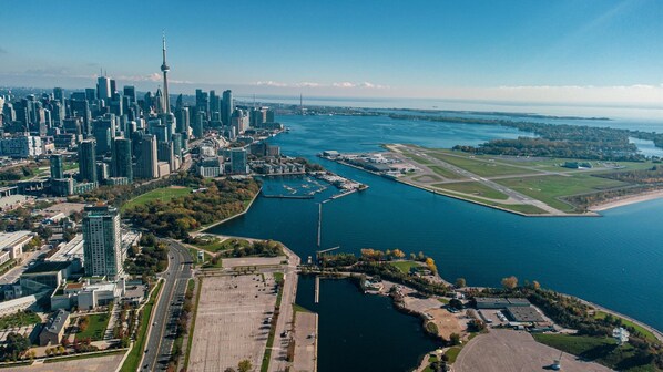 An aerial view of a city with a prominent skyscraper, a marina, and a large body of water.