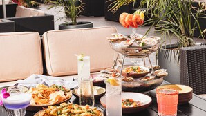 Un espacio para comer en la azotea con mesas al aire libre, diversos platos y bebidas.