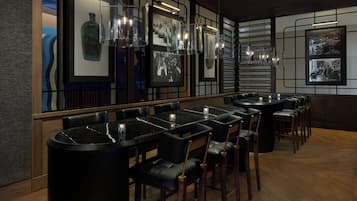A restaurant with black marble tables and chairs, framed photographs on the walls, and pendant lighting.