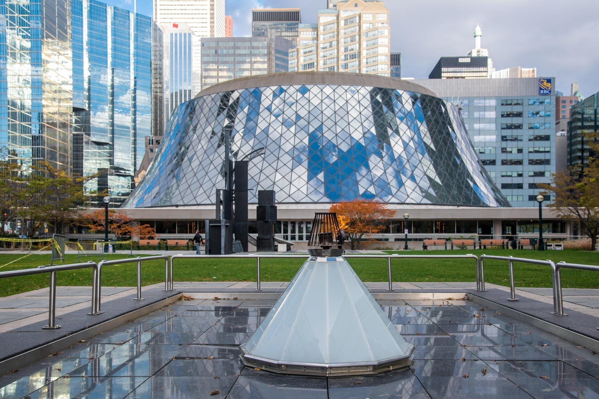 A modern building with a glass facade and a unique conical roof structure.