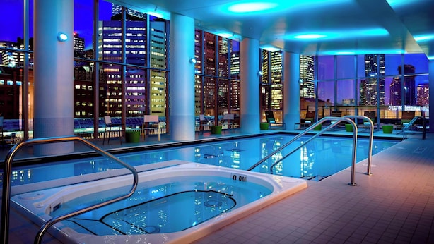 Una piscina interior con vistas a la ciudad, amplias ventanas y arquitectura moderna.