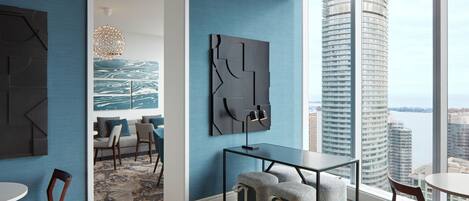 Interior moderno com área de refeições, uma grande pintura abstrata e vista para edifícios altos.