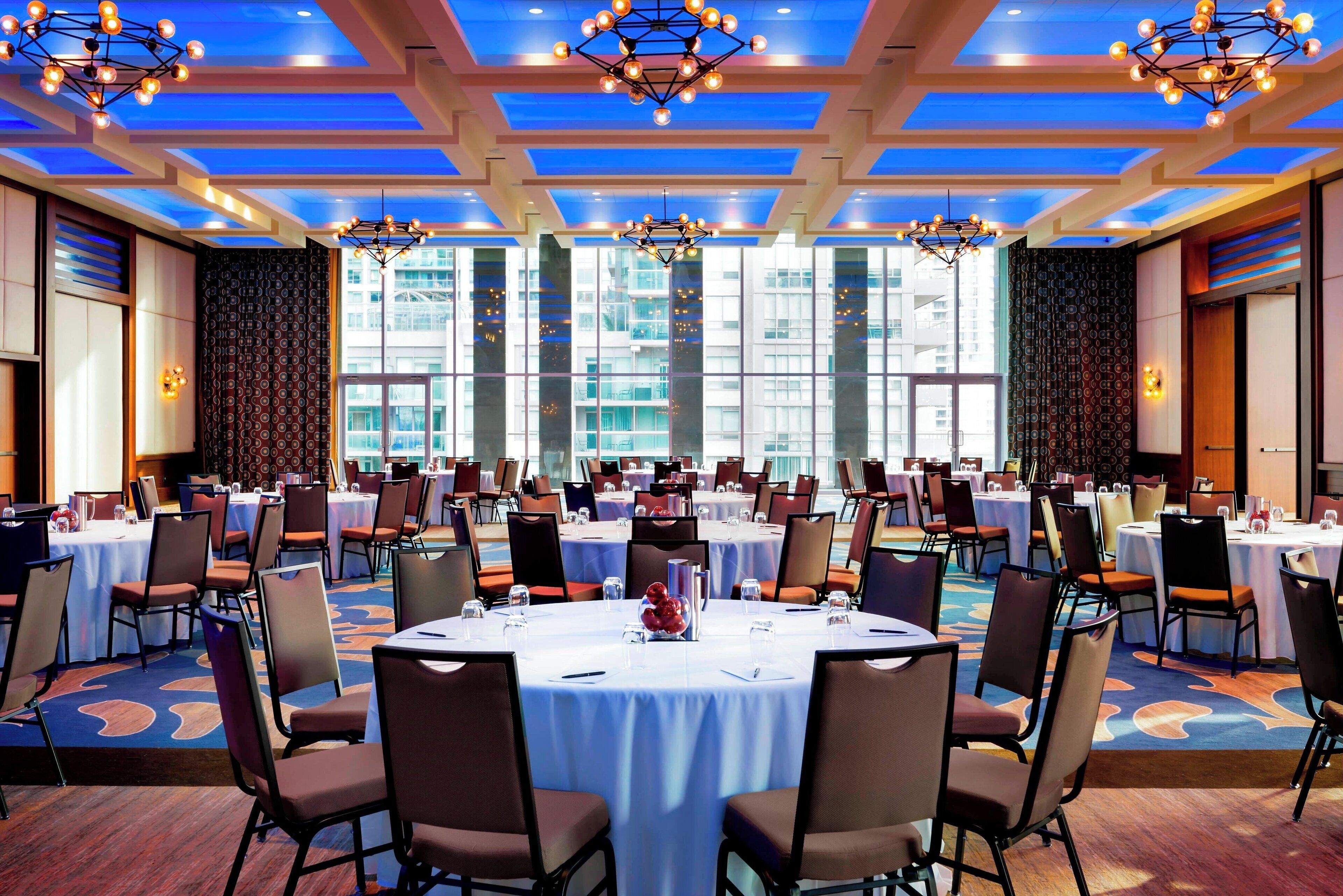 A conference room with round tables, chairs, and a patterned carpet.