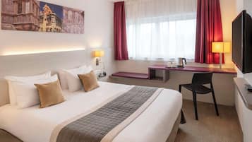 Een hotelkamer met een groot bed, een bureau, een stoel, een televisie en een schilderij aan de muur.